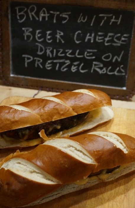 Brats with Warm Beer Cheese Drizzle on Pretzel Roll photo by Kathy Miller
