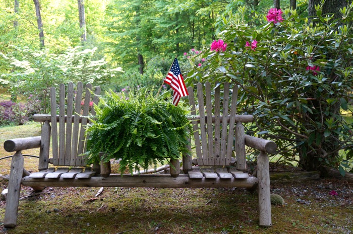 Mountain bench with fern and American flag photo by Kathy Miller