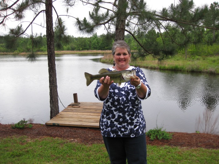 Joy McCabe holding bass at the pond house photo by Joy McCabe