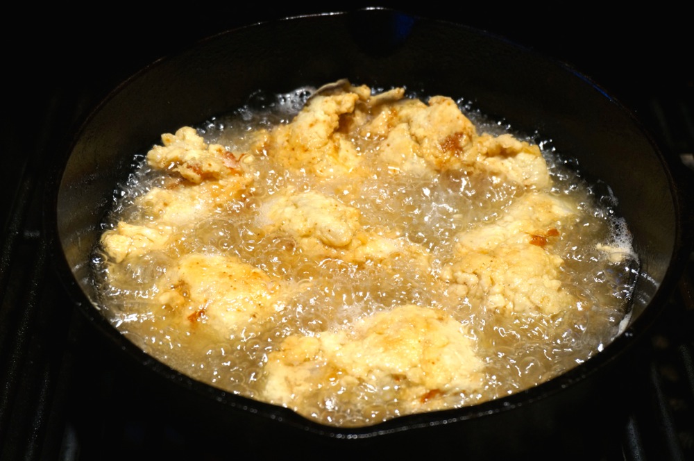 Frying the Chicken Drummettes in a cast iron pot on grill photo by Kathy Miller