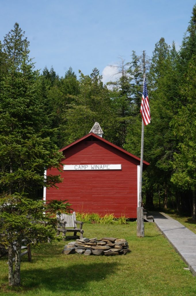 The lakeside boathouse, firepit and flag at Camp Winape photo by Kathy Miller