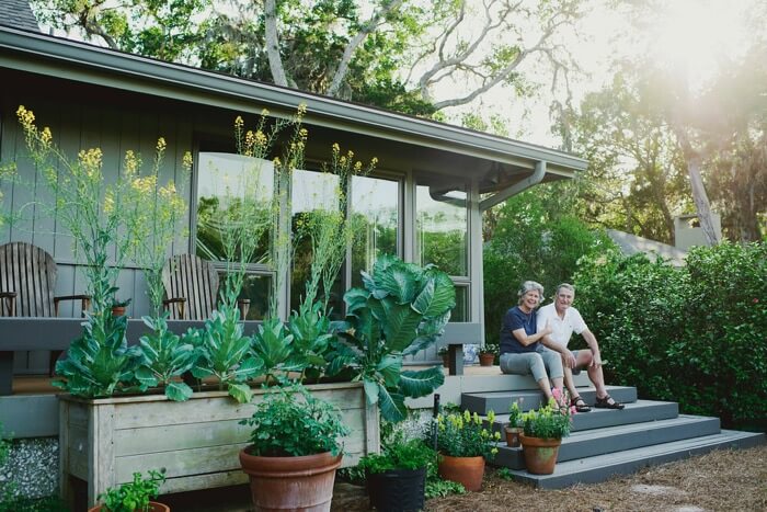 Paula and Bronson Lamb on porch with collard greens and tomato plants photo by Page Tehan