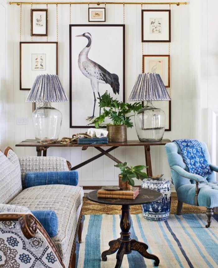 Living room with bird prints hanging by chains from brass rod 