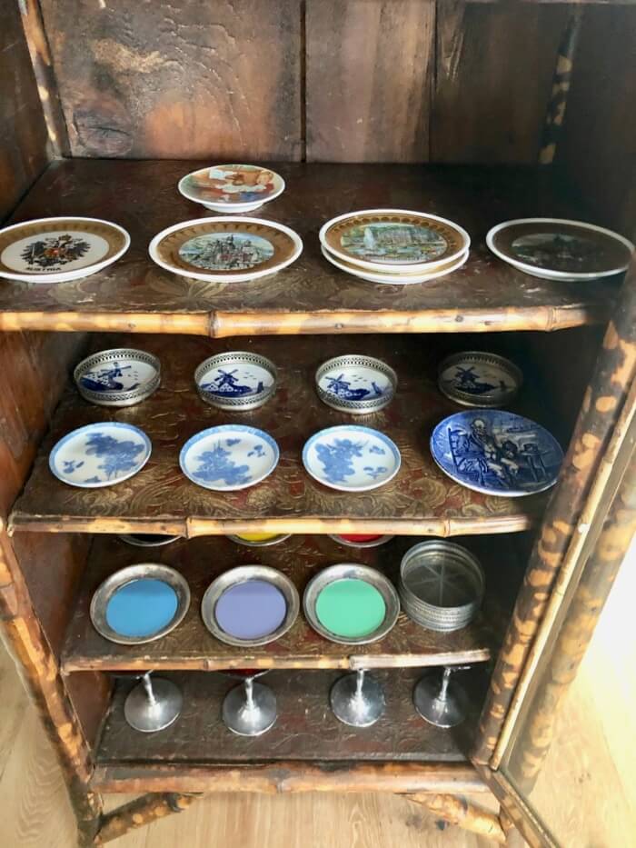 Old coaster collection in antique bamboo cabinet photo by Kathy Miller