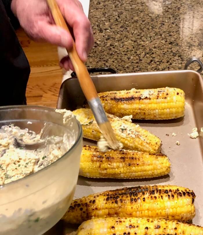 Lathering the Grilled Corn with Cotija cheese mixture