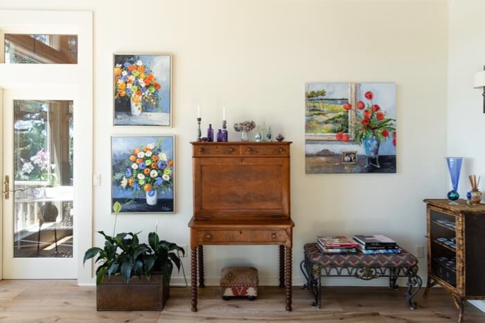 Sunroom with antiques and bright Kathy Miller original floral paintings photo by Lynn Tennille